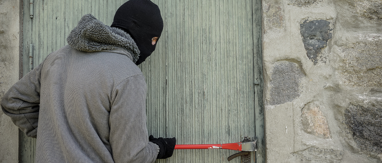 Einbrecher mit einem Brecheisen vor einer Haustür